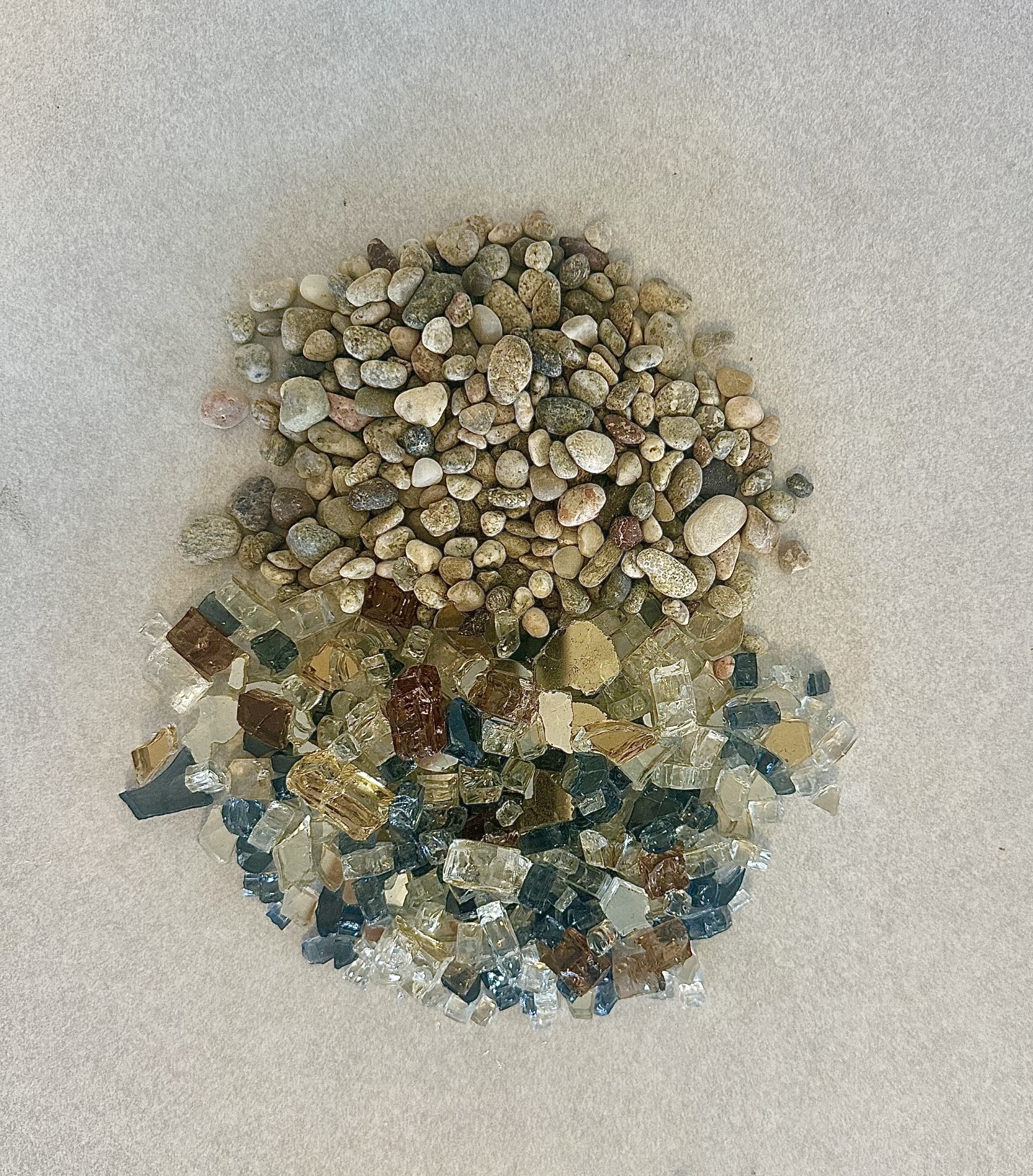 Top-down material study of river pebbles and decorative landscape glass.