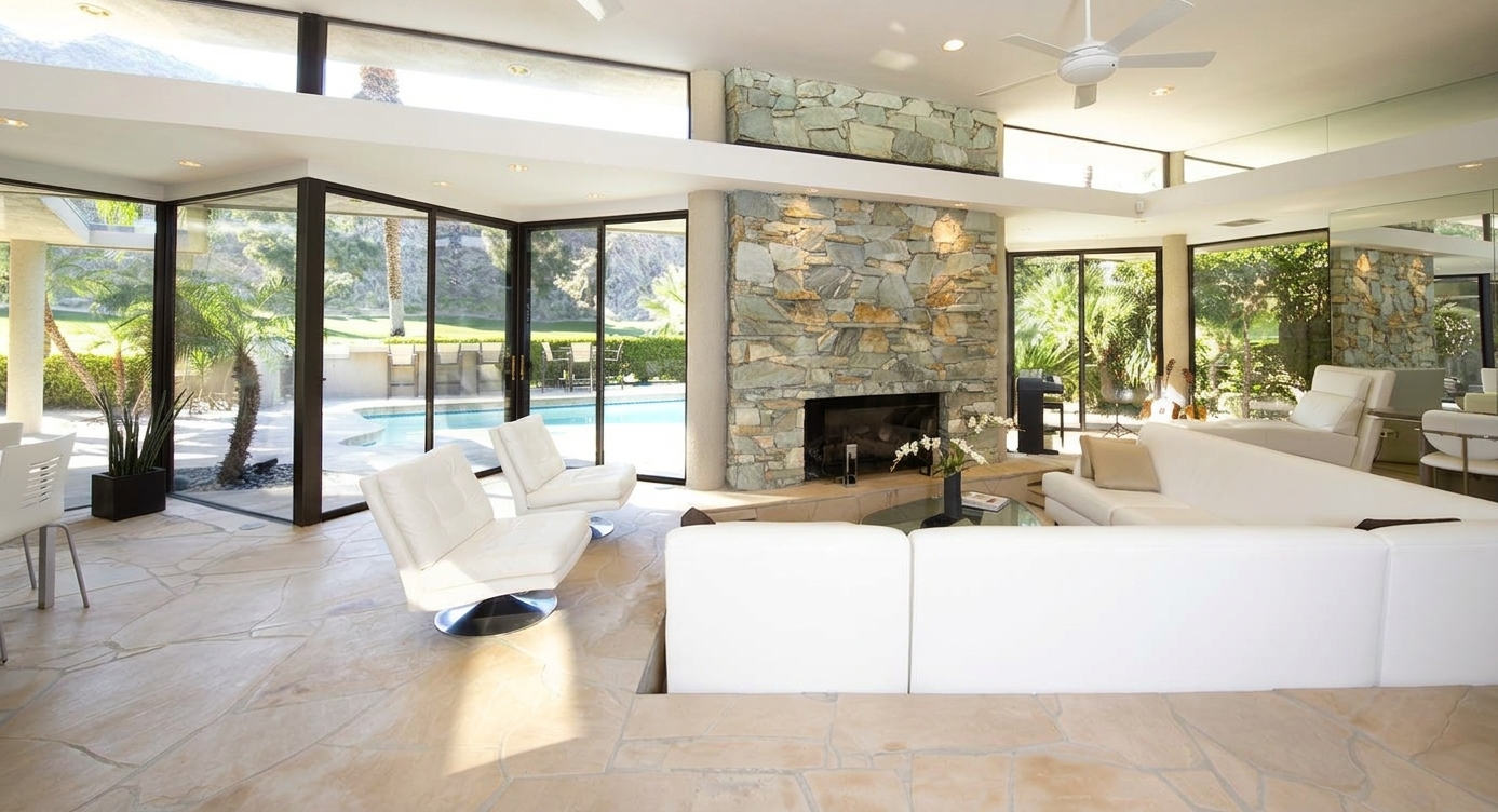 Sunlit modern living room with floor-to-ceiling glass doors opening to a pool, custom glass installation in the Coachella Valley by Holland Glass & Mirror