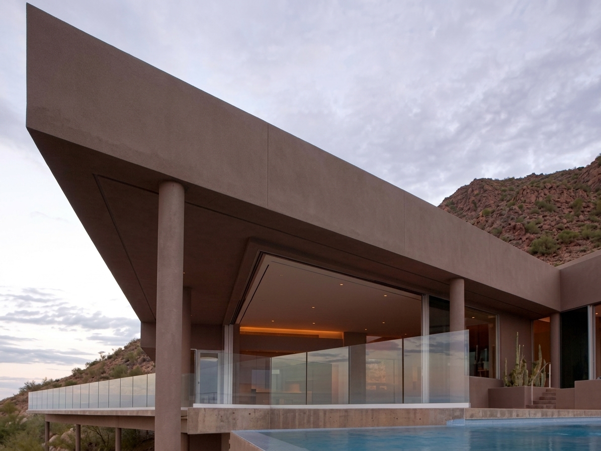 Desert home at dusk with frameless glass windbreak panels along the terrace and pool in the Coachella Valley