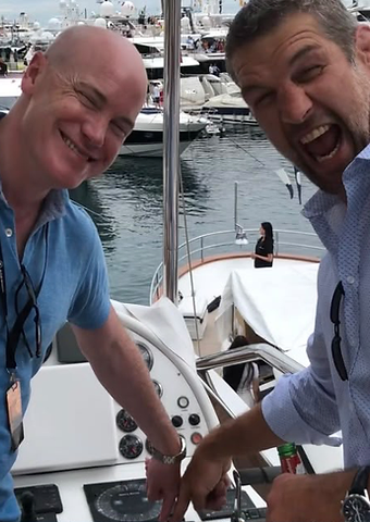 Two guests laughing on the helm of a yacht in the Monaco marina