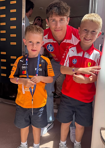 F1 driver Arthur Leclerc posing with two young guests in the paddock