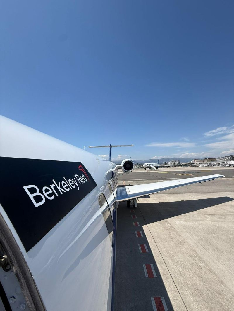 Berkeley Red branded private jet on the tarmac under a clear blue sky