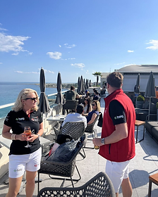 Berkeley Red hosts with guests on an oceanfront terrace