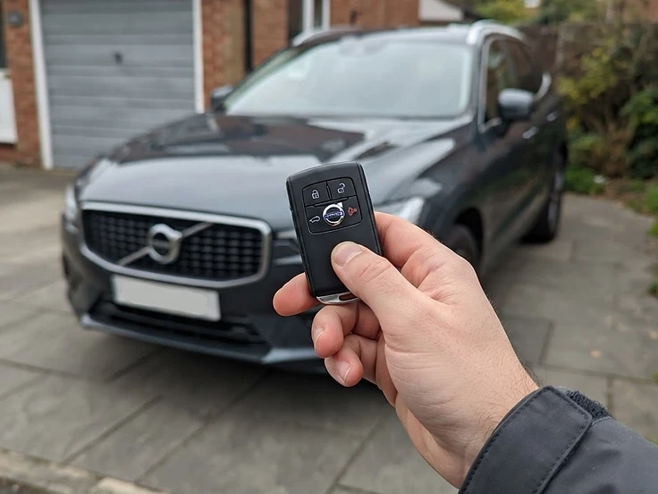 Volvo key fob held in front of a Volvo XC60