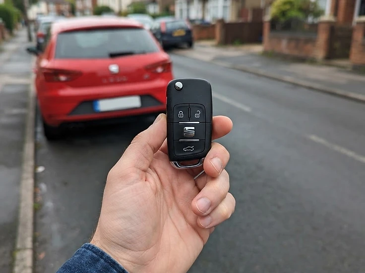 SEAT key fob held in front of a SEAT Leon