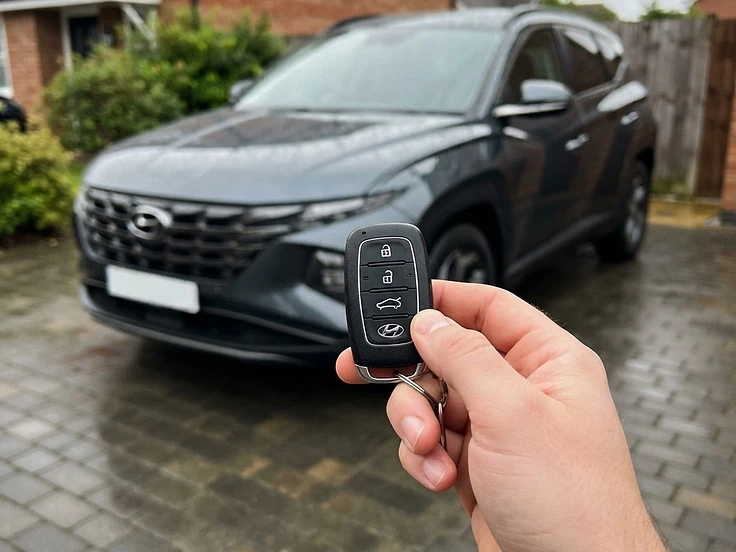Hyundai key fob held in front of a Hyundai Tucson