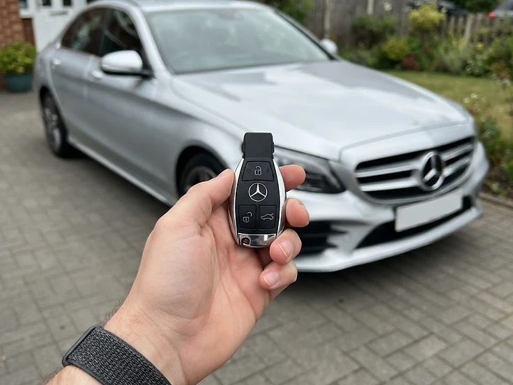 Mercedes-Benz key fob held in front of a Mercedes-Benz C-Class