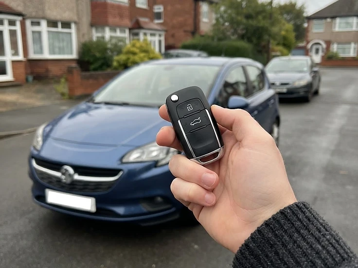 Vauxhall key fob held in front of a Vauxhall Corsa