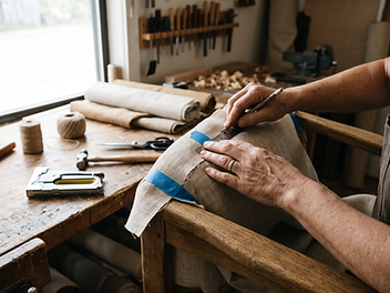 Skilled hands measuring fabric on a timber chair frame in the DOMEN workshop