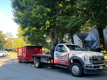 White Veterans Roofing Ford Super Duty truck towing a red branded debris trailer on a residential street