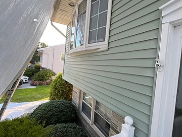 White tarp held taut with extension ladder during roof prep