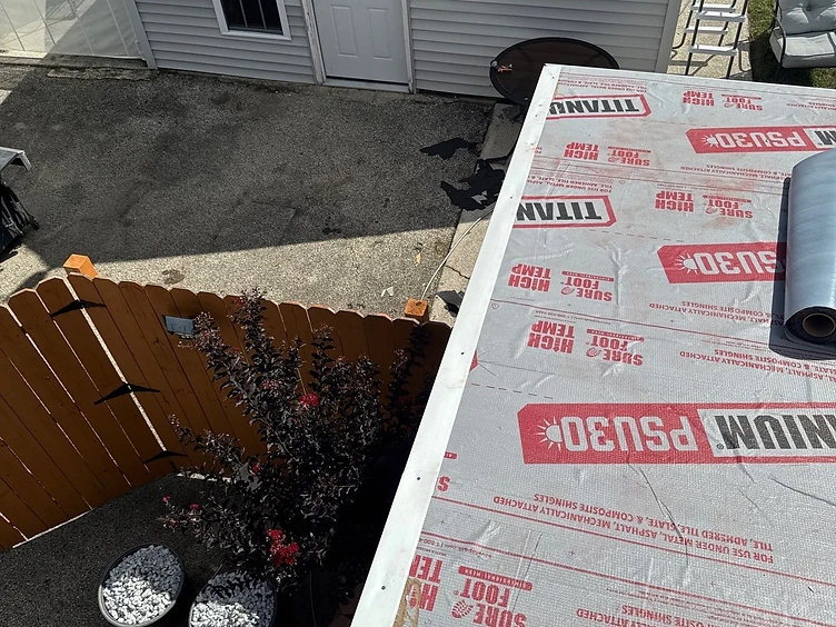 White metal drip edge fastened along the diagonal rake edge of a roof deck covered in grey TITANIUM PSU30 underlayment with visible nails