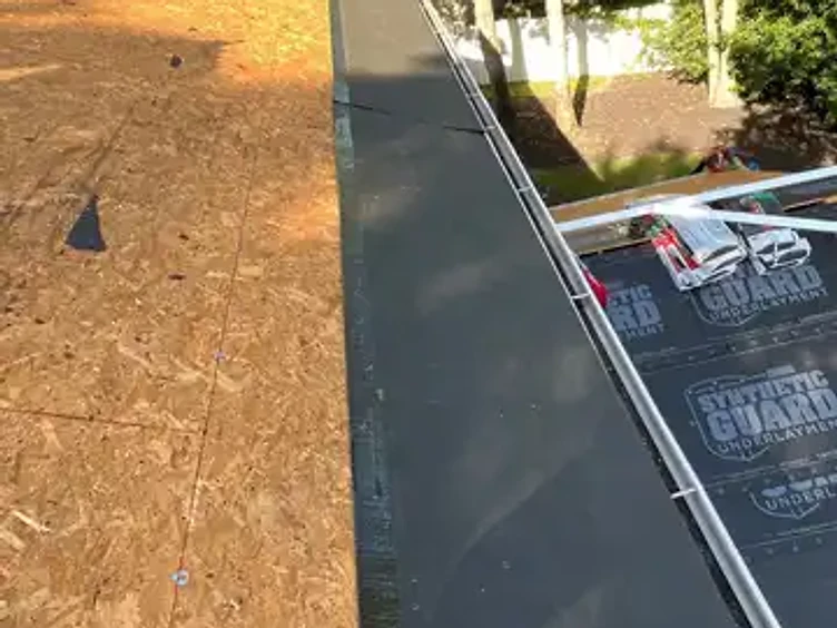 Dark adhesive ice and water shield installed as a horizontal strip along the bottom eave edge of a roof over exposed OSB decking