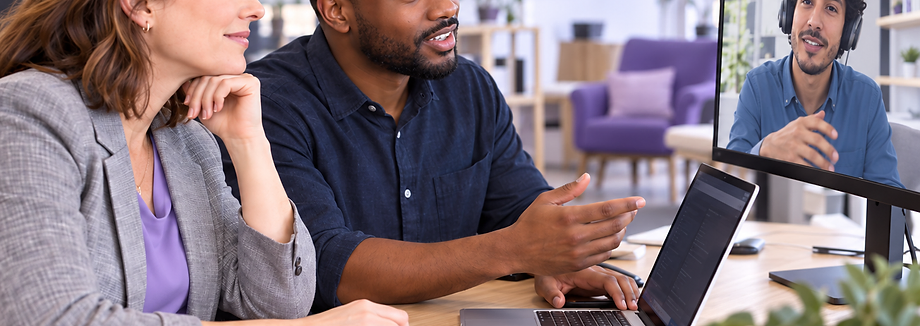 Two colleagues collaborating at a desk with a remote colleague on screen