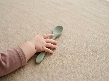 Main de bébé atteignant une cuillère en silicone