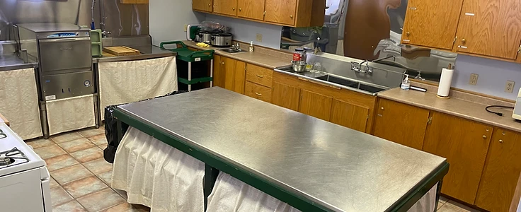 The commercial kitchen with stainless prep island, stove and cabinets