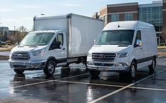 Clean white commercial box truck and service van parked in a paved lot