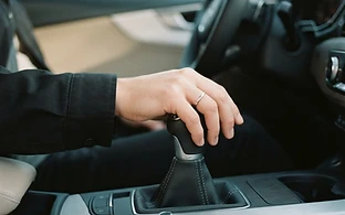 A hand resting on a manual gear stick inside a car