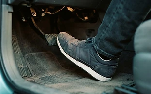 A driver's foot pressing the pedal of an automatic car