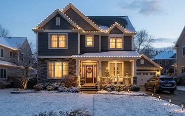 A home roof line outlined in warm white holiday lights on a cold clear evening.