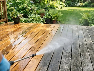 A wooden deck half washed clean and half still weathered grey.