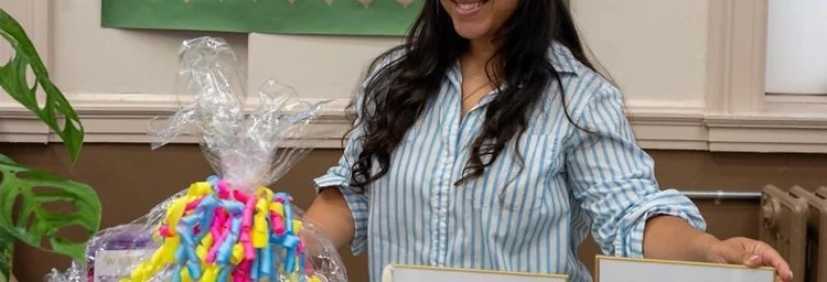 A Post Care volunteer beside welcome signs and a care package gift basket