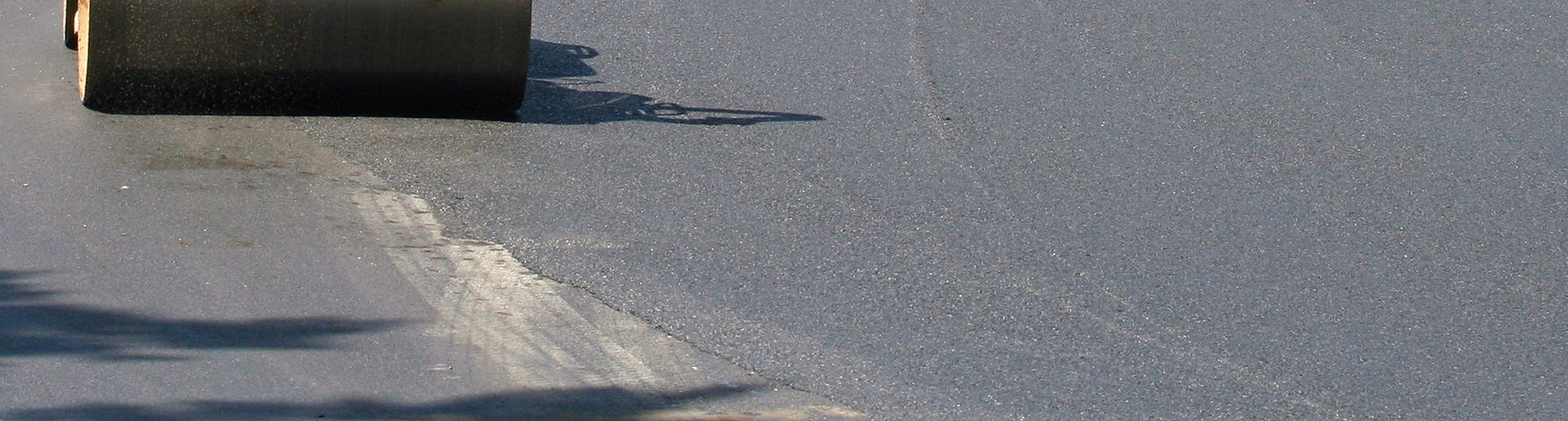 Heavy construction roller smooths out a fresh layer of hot tarmac
