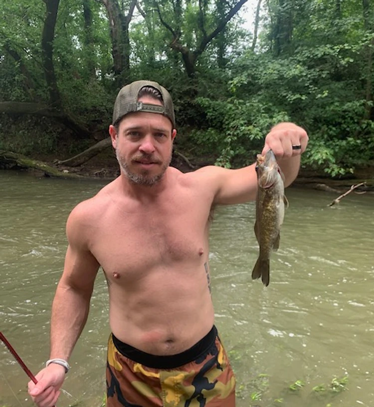 Man standing in a shallow stream, lean build