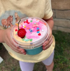 Child holding a finished pink and blue slime creation