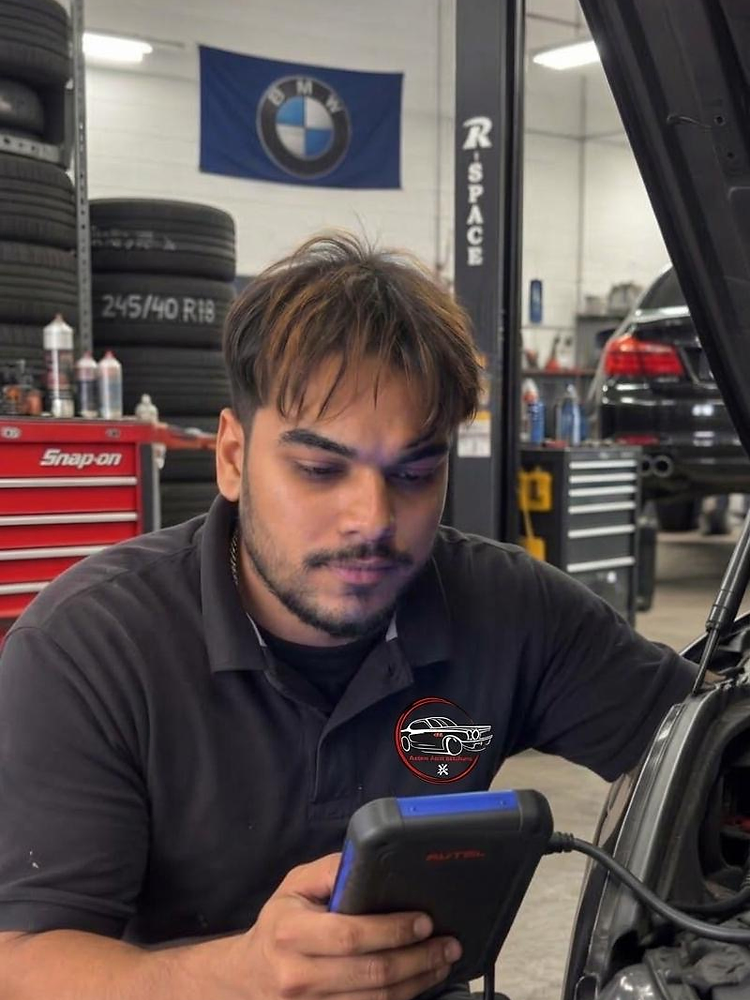 Azeem Auto Solutions technician running computer diagnostics beside an open hood