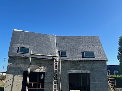 Toiture neuve en ardoises terminée avec fenêtres de toit sur maison en construction