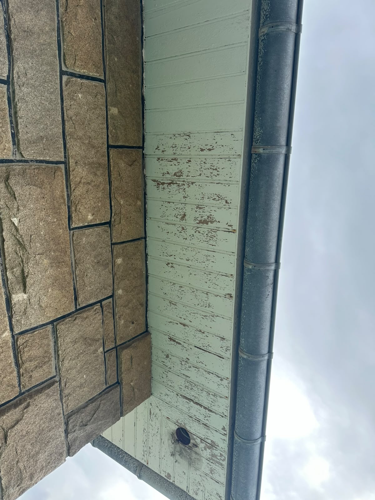 Lambris de débord de toit écaillé et abîmé par l'humidité avant rénovation par RP Couverture