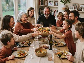 A large family passing a dish around a long wooden table, laughing together.