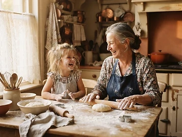 A grandmother and granddaughter rolling out dough together, flour on their hands.