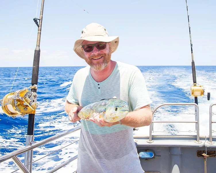 Angler holding a freshly caught mahi-mahi on a charter boat