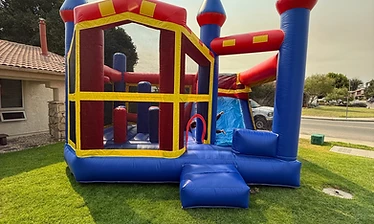 Castle Slide Combo bounce house with an attached blue slide in bold red, blue and yellow, set up on a Central Coast lawn