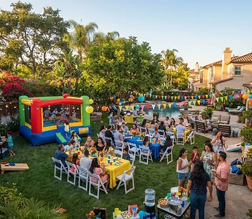 Backyard party setup with a bounce house, tables and chairs in a sunny California yard