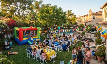 Backyard party setup with a bounce house, tables and chairs in a sunny California yard