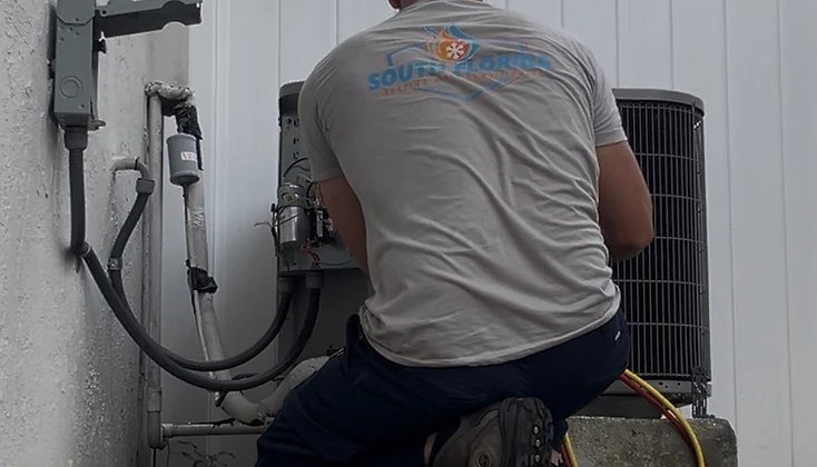 South Florida Heating and Air Conditioning technician servicing a condenser unit outside a home