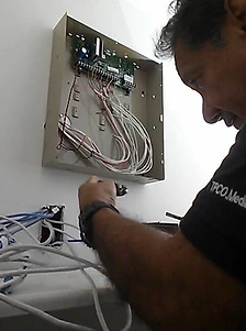 Technician wiring a wall-mounted low-voltage enclosure