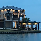 Waterfront home at dusk with exterior lighting