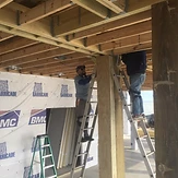 Technicians prewiring an elevated framed structure