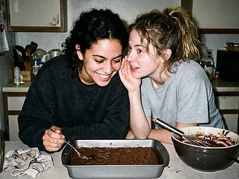 Two friends sharing a late-night moment over a fresh pan of brownies