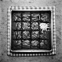 A tin of chocolate brownies with one corner piece missing