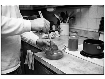 Adult hands stirring honey in a glass bowl on an ordinary home kitchen counter