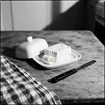 Dairy butter on a simple ceramic dish beside a gingham kitchen towel