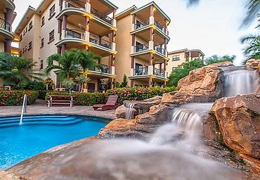 Resort villa beside a pool with a rock waterfall