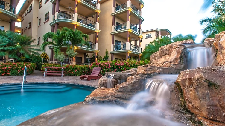Resort pool with rock waterfall and suites at dusk