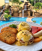 Eggs Benedict with hollandaise sauce, hash browns and fruit by the pool