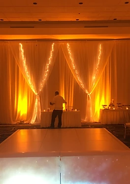Draped wall bathed in warm golden light with fairy light accents
